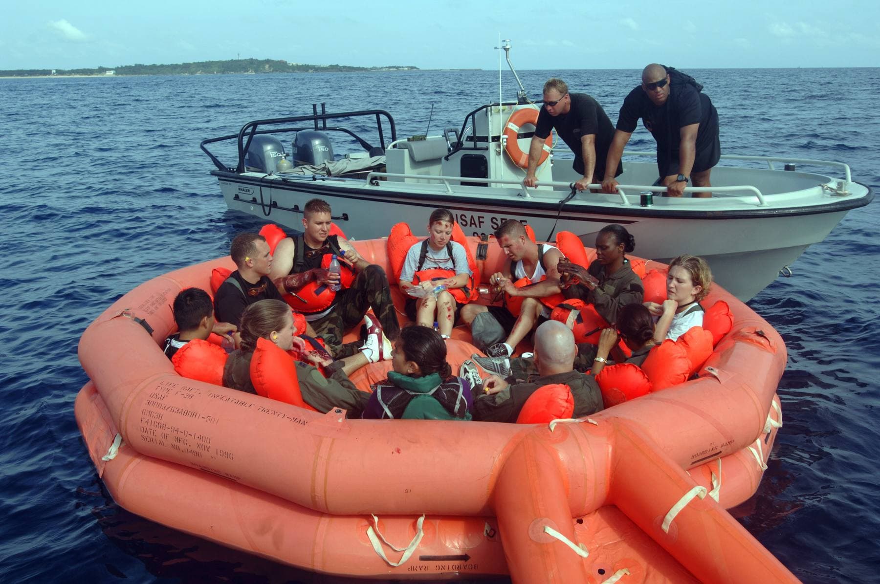 Pessoas numa balsa salva-vidas insuflada no mar, junto a uma pequena embarcação