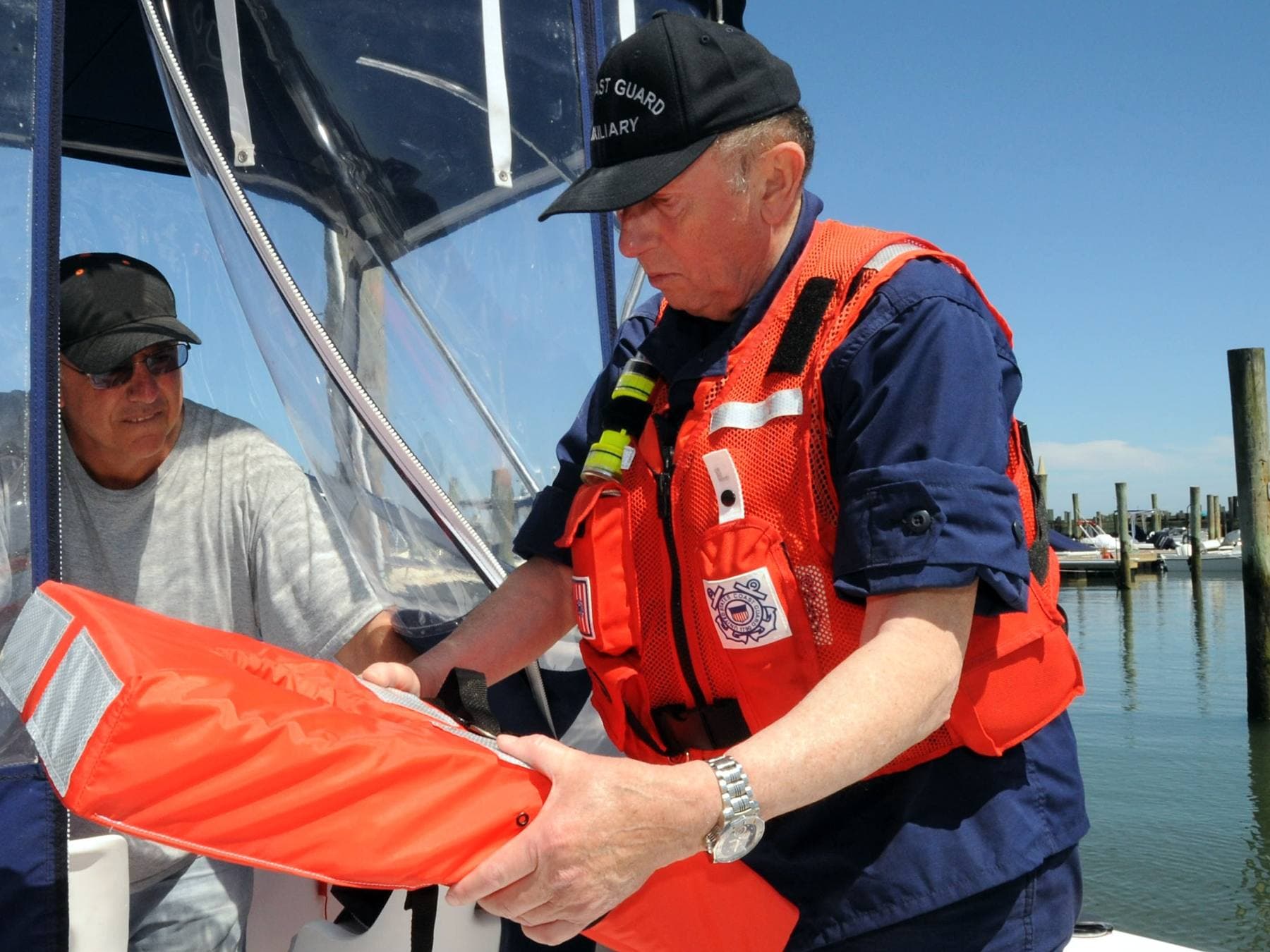 Inspetor a verificar um colete salva-vidas a bordo de uma embarcação atracada na marina, antes de sair